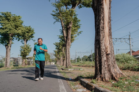 A man is jogging leisurely along a beautiful treelined street beneath a clear blue sky