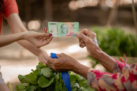 A vibrant scene that beautifully captures the financial exchange happening between a young buyer and an elderly vendorの写真素材