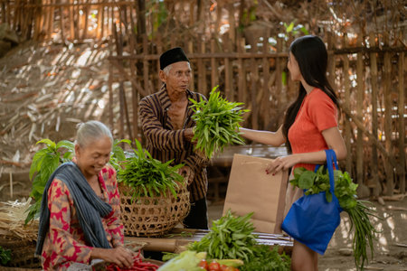 A vibrant and lively market scene showcases various farmers who are selling their fresh vegetables to a customerの写真素材