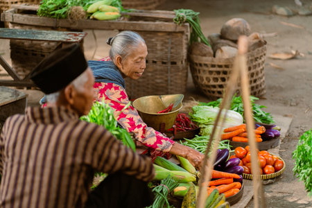 Elderly individuals sell vibrant, fresh vegetables at a bustling market, showcasing community spirit and traditionの写真素材