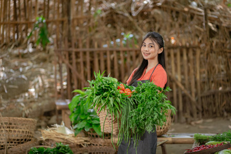 A cheerful woman carrying a basket filled with an assortment of fresh vegetables, representing rural farming lifeの写真素材