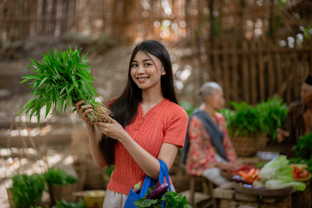 A joyful young woman displays fresh herbs at a lively outdoor market, surrounded by vibrant community lifeの写真素材