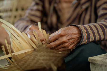 A close-up of skilled hands weaving a basket with natural materials, showcasing traditional craftsmanship.の写真素材
