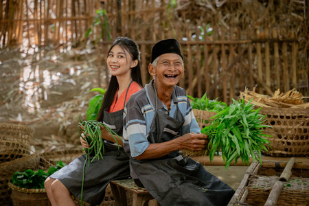 Two cheerful farmers laugh together while harvesting fresh vegetables in a rustic, peaceful settingの写真素材