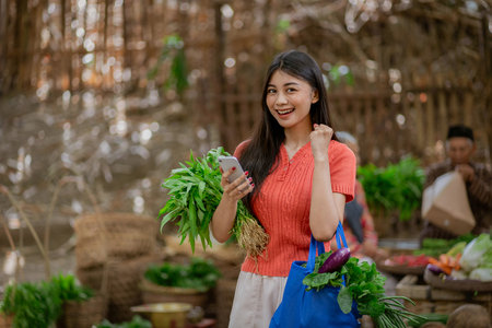 A joyful and happy young woman is happily shopping for fresh produce at a vibrant, bustling local marketの写真素材