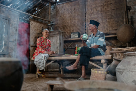 An elderly couple shares warm stories in their cozy, rustic home filled with traditionの写真素材