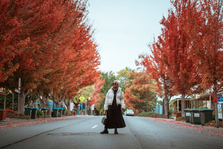 A lone person stands among colorful autumn trees on a quiet streetの写真素材