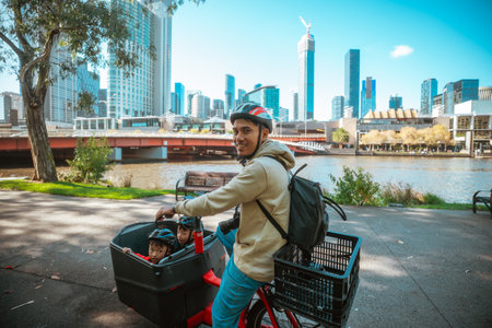 A happy family bikes together along a scenic riverside path in a busy cityの写真素材