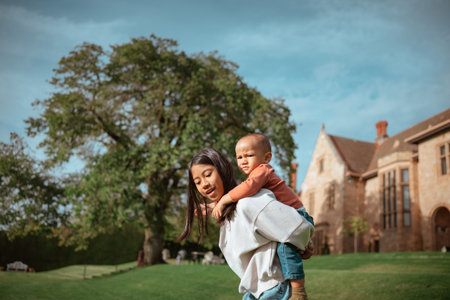 A heartwarming scene of a loving mother carrying her happy child outdoors, surrounded by stunning natureの写真素材