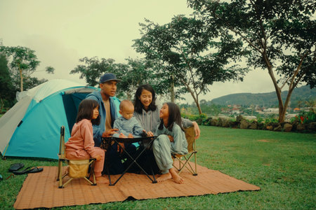 A joyful family happily enjoys camping together outdoors, bonding in the beautiful embracing nature around themの写真素材
