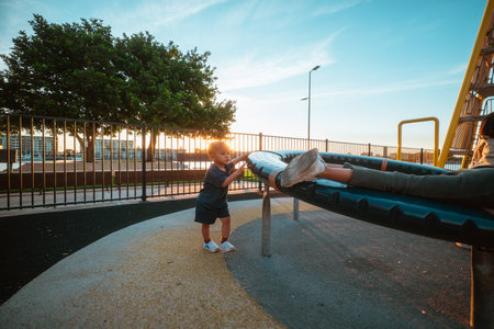 children happily swinging during sunset hoursの写真素材