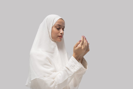 woman in white headscarf gazing at cupped hands with focused expression, conveying private