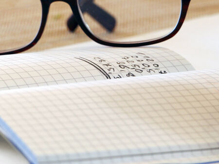 notebook with  handwritten numbers and glassesの写真素材