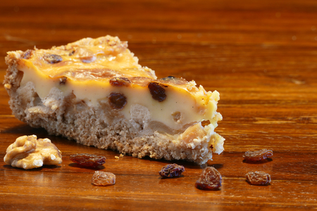 piece of cake on a wooden brown table, some raisins and walnuts, copy spaceの写真素材