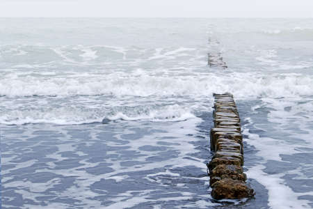 old wooden breakwater and waves, stormy weather at Baltic Sea, copy spaceの写真素材
