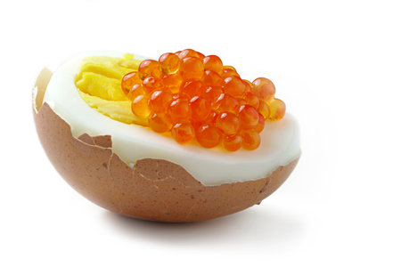 half of a boiled egg in the shell with red slamon caviar, close up isolated on white backgroundの写真素材
