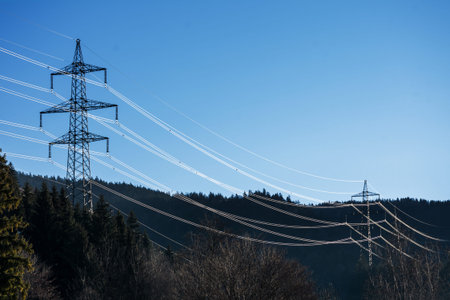 high voltage transmission line across the forest, copy space in the blue sky
