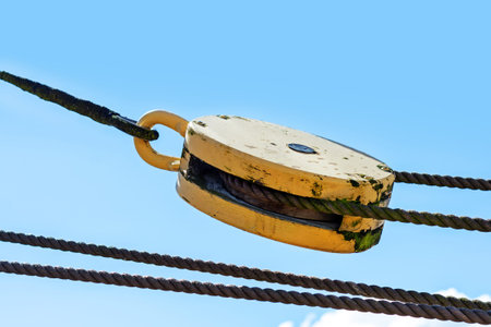 pulley with ropes from an ancient sailing vessel against the blue summer sky, copy space in the...