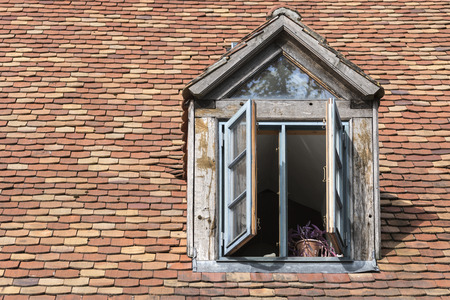 open window in an old dormer made of wood on a roof with historic beaver tail tiles, copy spaceの写真素材