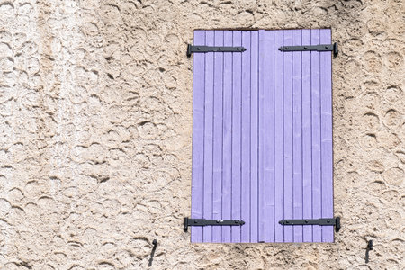 closed window shutters made from purple painted wood in a rough plastered wall, copy spaceの写真素材