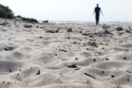 blurred silhouette of a man walking on the beach, selected focus in the foreground, narrow depth of fieldの写真素材