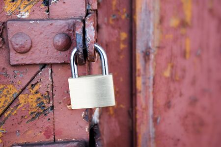 new padlock on an old red wooden gate, selected focus, narrow depth of field, copy space in the blurry backgroundの写真素材