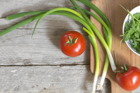 healthy cooking, organic tomatoes, spring onions and arugula on a rustic wooden table with copy space, view from aboveの写真素材