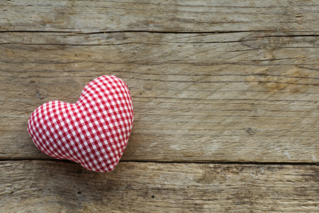 heart made of cloth with red white checkered pattern on rustic old wood with copy space, concept of love at Christmas, Mother's Day or Valentine's Dayの写真素材