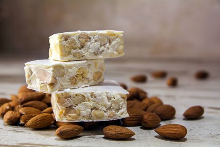 Italian festive torrone or nougat and almonds on a rustic wooden table, copy space, close up with selected focus, very narrow depth of fieldの写真素材