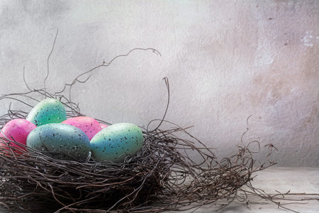 Easter nest with colored eggs in pastel pink and blue turquoise on rustic wooden planks against a...