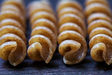 macro shot of wholemeal pasta fusilli from organic whole grain spelt on dark wood, selected focus and extremely narrow depth of fieldの写真素材