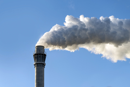 industrial smoke from a chimney against the clear blue sky with copy spaceの写真素材