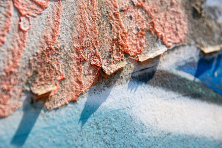background texture of a wall with exfoliated plaster in bright red, blue and gray, abstract closeup...