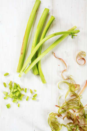 rhubarb stalks, sliced pieces and spirals from the peel on a white painted wooden background, view from above, verticalの写真素材