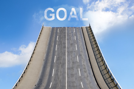 Road leads upwards in the blue sky with white clouds, text GOAL, business concept for new goals, future and successの写真素材