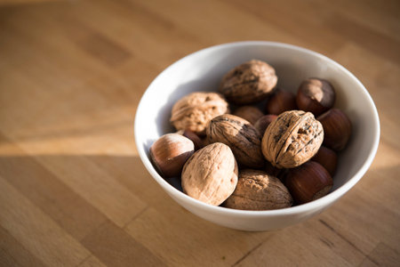 Fresh walnuts in a white bowl on a wooden table, copy space, selective focus, narrow depth of field