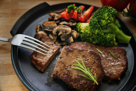 beef steak with vegetables like broccoli, mushrooms and tomatoes on a gray plate, selected focus, narrow depth of fieldの写真素材