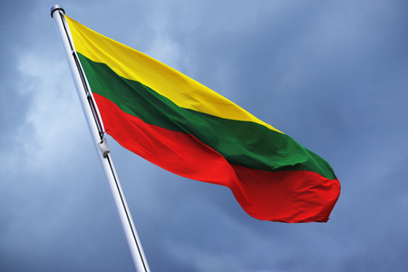 Flag of Lithuania with stripes in yellow, green and red, national symbol or sign of the country, fluttering in the wind against the cloudy sky on a sunny dayの写真素材