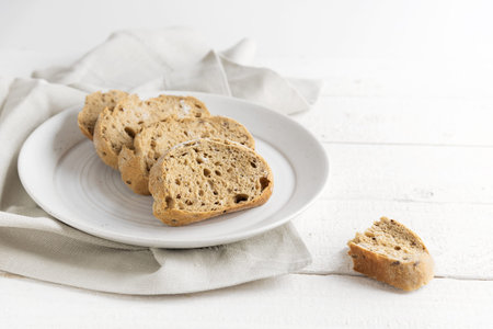 fresh wholemeal bread on a plate, on a white painted rustic wooden table, copy space, selected...