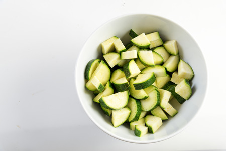 sliced zucchini, prepared vegetables in a white bowl on a light gray background, copy space, top view from aboveの写真素材