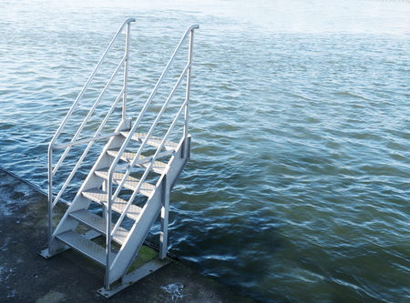 stairs of metal at the harbor leads upward to nothing, only water, copy spaceの写真素材