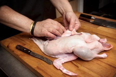 male hands prepare a raw duck for cooking on a rustic wooden butcher block, selected focus, narrow depth of fieldの写真素材