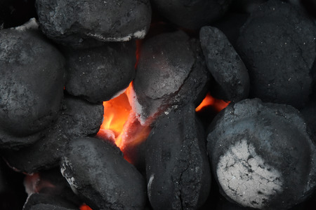 glowing charcoal briquettes in a barbecue grill, close up, background with copy space, selected focusの写真素材