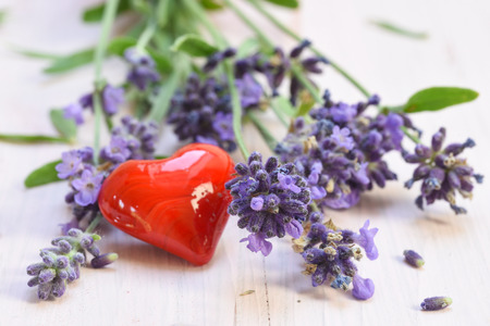 blooming lavender and a red heart from glass on a white painted wooden backgroundの写真素材