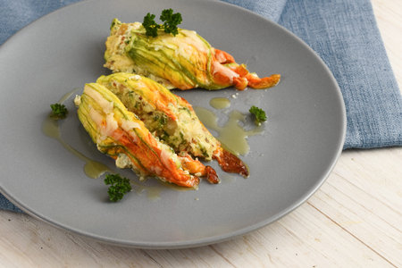 stuffed zucchini or courgette blossoms baked with parmesan cheese and parsley garnish on a blue gray plate, selected focus, narrow depth of fieldの写真素材