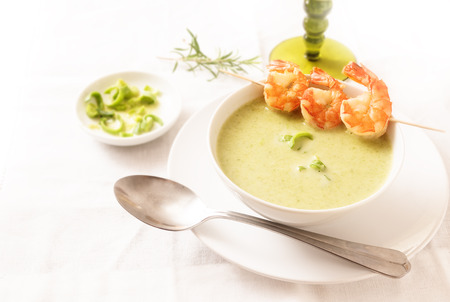king prawns with green vegetable cream soup on a white tablecloth, copy space, selected focus, narrow depth of fieldの写真素材