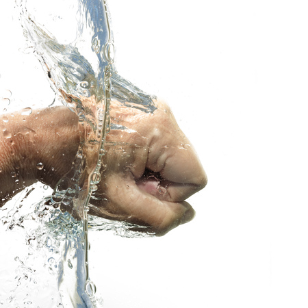 human fist beats through the water with splash, isolated on a white background, copy spaceの写真素材