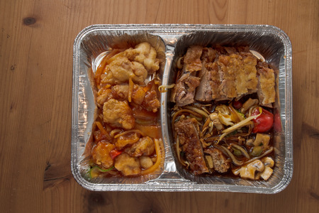 Asian fast food from delivery service in a foil on a wooden table, high angle view from aboveの写真素材