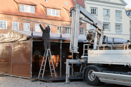 Preparation for the christmas market, man from behind is setting up a big tent in the cityの写真素材