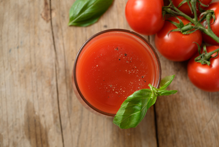 fresh tomato juice in a drinking glass with basil garnish on a rustic wooden board, healthy smoothie drink with copy space, selected focus, top view from aboveの写真素材